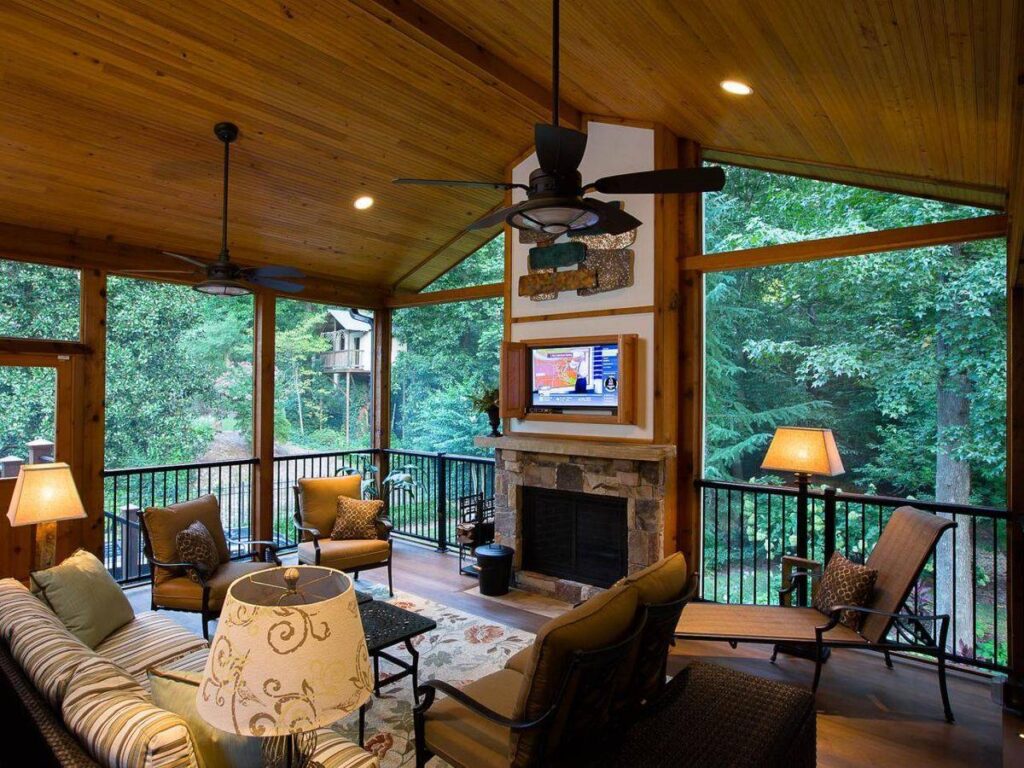 A screened porch equipped with a fireplace and a television, creating a comfortable outdoor living space.